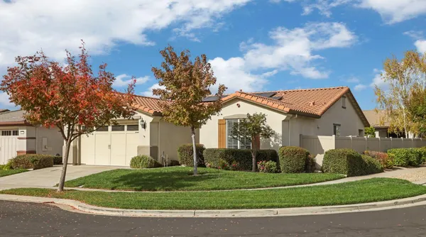 a view of a white house next to a yard with big trees