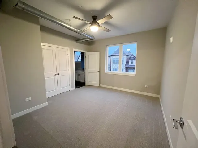 an empty room with chandelier fan and windows