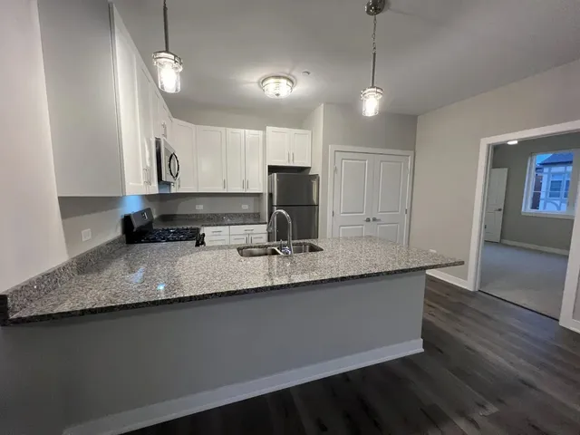 a kitchen with stainless steel appliances granite countertop a sink a stove and a wooden floors