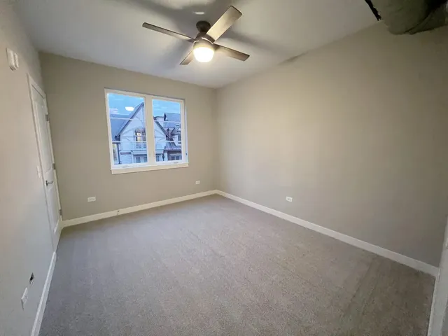 an empty room with a fan & a window