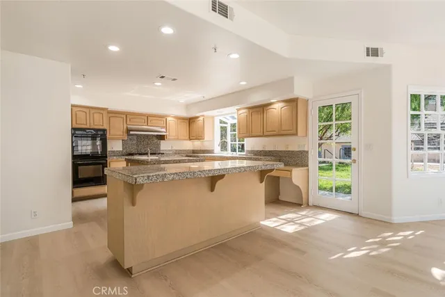 a kitchen with kitchen island granite countertop a stove and a sink