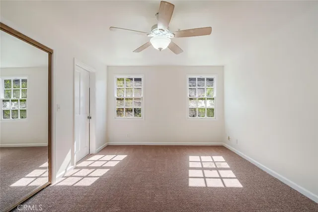 an empty room with windows and ceiling fan