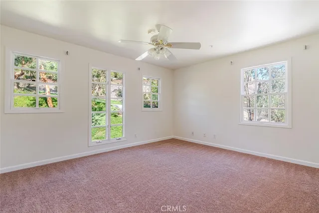 an empty room with windows and chandelier fan