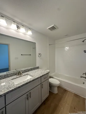 a bathroom with a granite countertop sink a toilet and bathtub