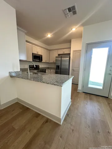 a large kitchen with stainless steel appliances granite countertop a stove a sink and a microwave