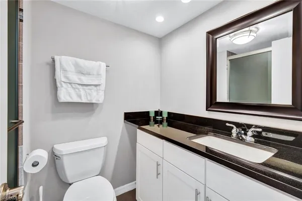 a bathroom with a granite countertop toilet sink and mirror