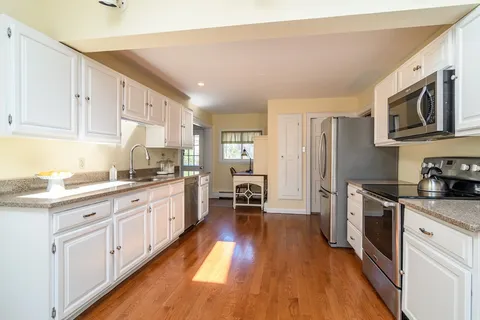 a large kitchen with stainless steel appliances granite countertop a stove a sink dishwasher and a refrigerator with wooden floor