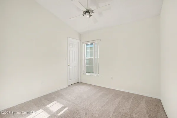 an empty room with windows and fan
