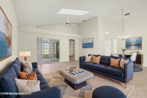 a living room with furniture kitchen view and a chandelier