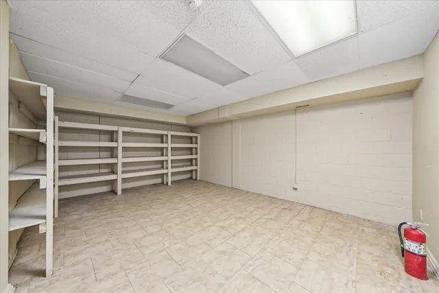 a view of a white house in front of a big yard with large trees and plants