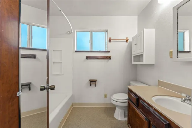 a bathroom with a granite countertop toilet a sink and a mirror
