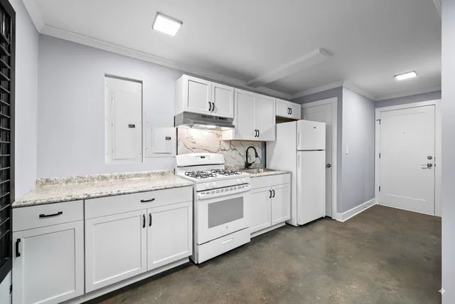 a kitchen with granite countertop white cabinets and white appliances