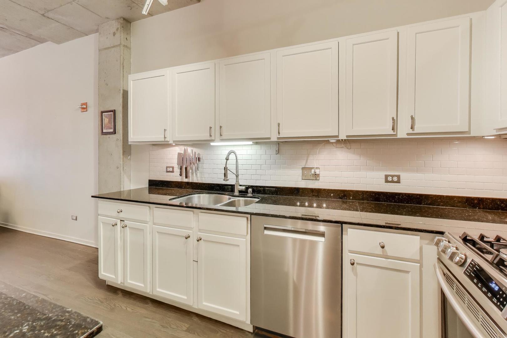933 West Van Buren Street, Unit 504 Chicago, IL 60607 - Photo 13 of 31 a kitchen with granite countertop white cabinets and white appliances