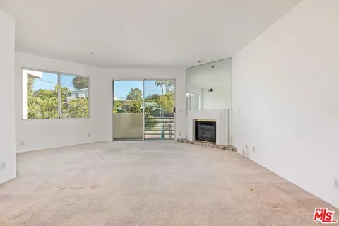 an empty room with windows and fireplace