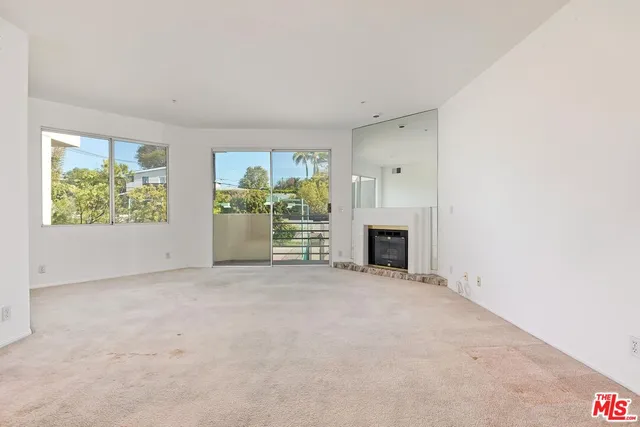 an empty room with windows and fireplace