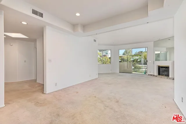 an empty room with windows and fireplace