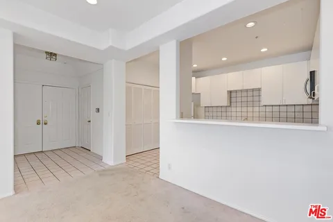 a view of an empty room with kitchen and a window