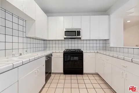 a kitchen with granite countertop white cabinets stainless steel appliances and sink