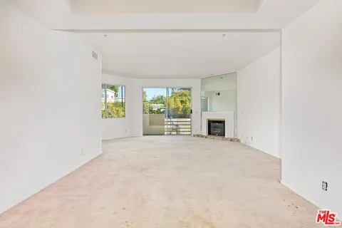 an empty room with windows and fireplace