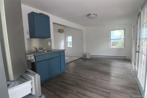 a kitchen with stainless steel appliances granite countertop a refrigerator a sink a stove white cabinets and wooden floor