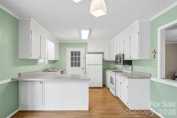 a kitchen with a sink a white cabinets and white appliances