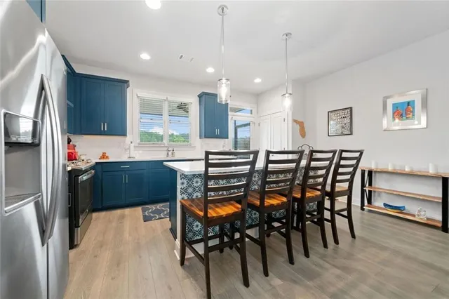 a kitchen with stainless steel appliances kitchen island granite countertop a table chairs and a refrigerator
