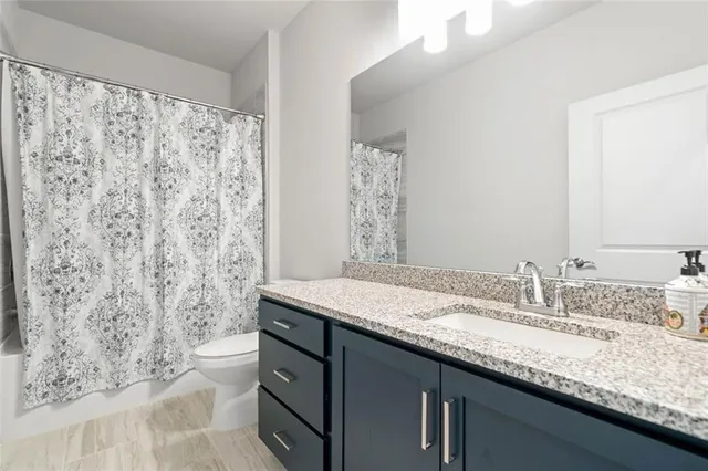 a bathroom with a granite countertop sink a toilet and a mirror