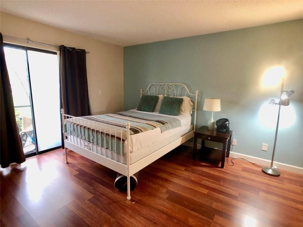 10026 Winding Lake Road, Unit 102 Sunrise, FL 33351 - Photo 12 of 23 a bedroom with a bed and wooden floor