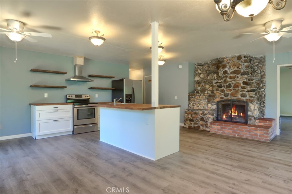 4949 Indian Peak Road Mariposa, CA 95338 - Photo 14 of 56 a large kitchen with cabinets wooden floor and a fireplace