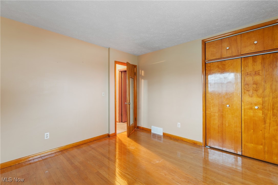 241 Baker Street Rittman, OH 44270 - Photo 15 of 25 Unfurnished bedroom with a closet, light hardwood / wood-style floors, and a textured ceiling