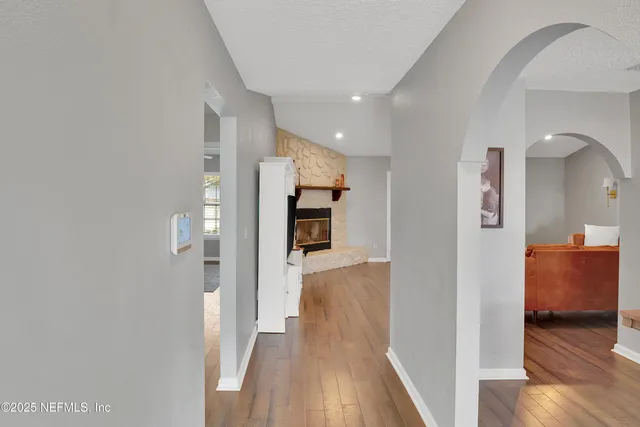 a view of a hallway with wooden floor and a living room
