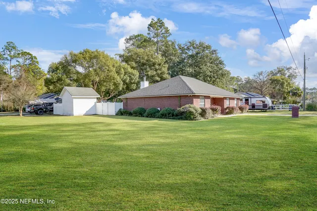 a front view of house with yard and trees in the background