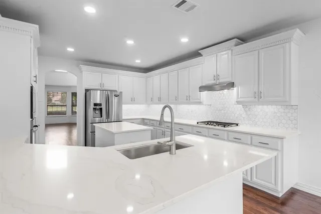 a kitchen with stainless steel appliances granite countertop a sink a stove and a refrigerator