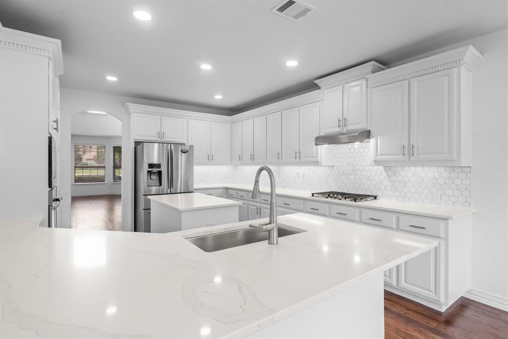 a kitchen with stainless steel appliances granite countertop a sink a stove and a refrigerator