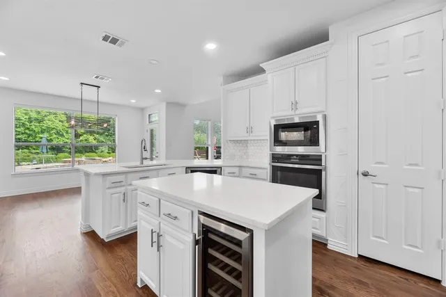 a kitchen with a sink a stove a microwave and white cabinets