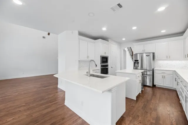 a kitchen with stainless steel appliances a refrigerator sink and white cabinets