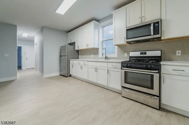 a kitchen with granite countertop a stove top oven microwave and cabinets