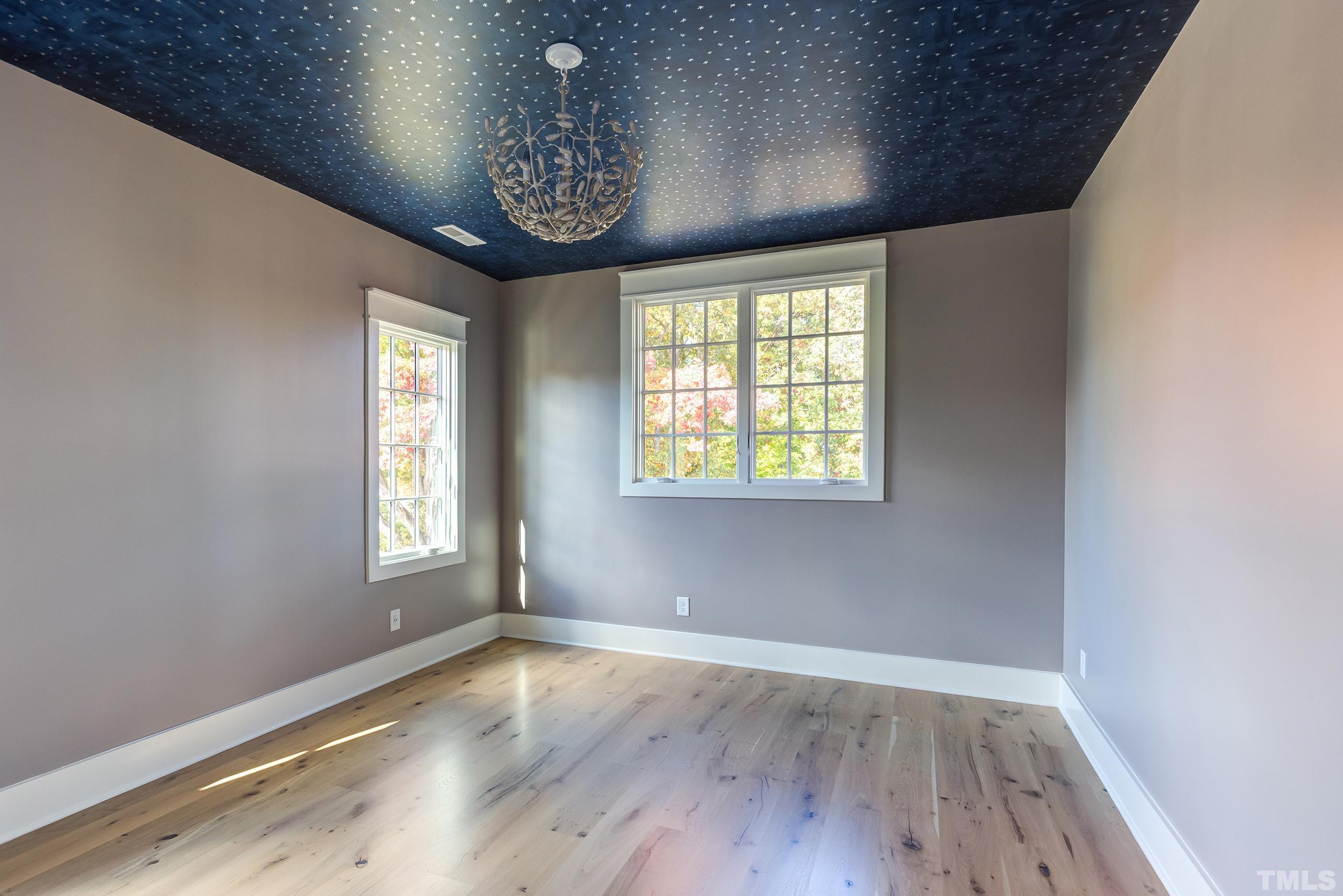 622 Shelley Road Raleigh, NC 27609 - Photo 8 of 26 an empty room with wooden floor chandelier and windows