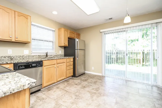a kitchen with granite countertop a stove a sink a refrigerator and a granite counter tops with white cabinets