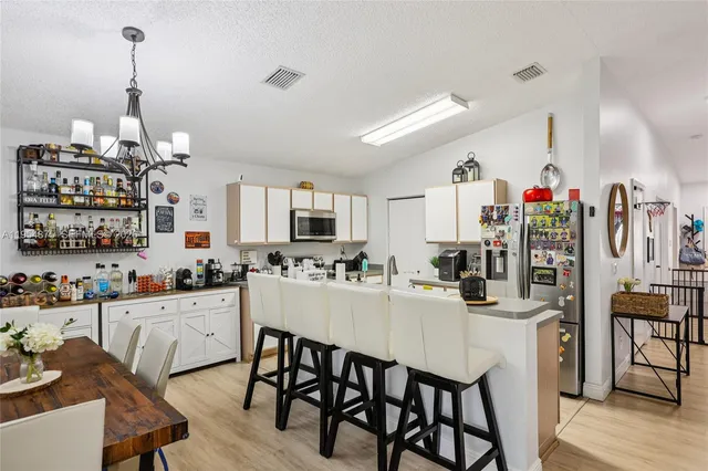 a kitchen with stainless steel appliances kitchen island granite countertop a dining table chairs and white cabinets