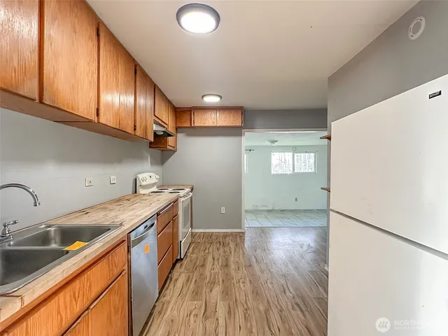 a kitchen with granite countertop a sink a stove top oven and cabinetry