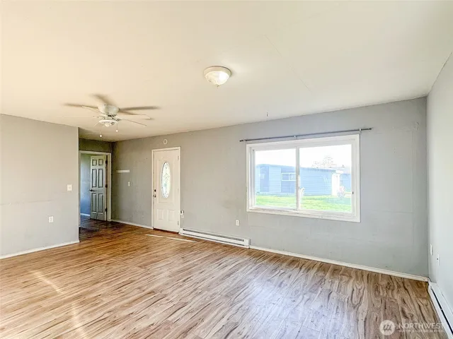 an empty room with wooden floor and windows