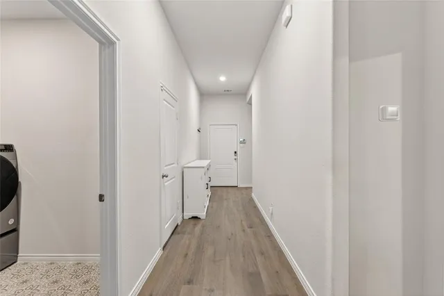 a view of a hallway with wooden floor and a bathroom