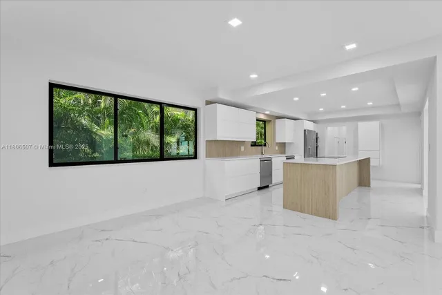 a view of kitchen with kitchen island stainless steel appliances wooden cabinets and window