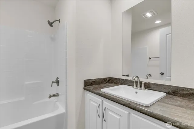 a bathroom with a granite countertop sink and a bathtub