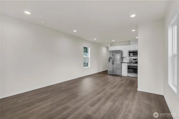 a kitchen with stainless steel appliances granite countertop a refrigerator a stove a sink and white cabinets