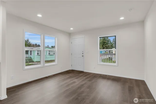 an empty room with wooden floor and windows