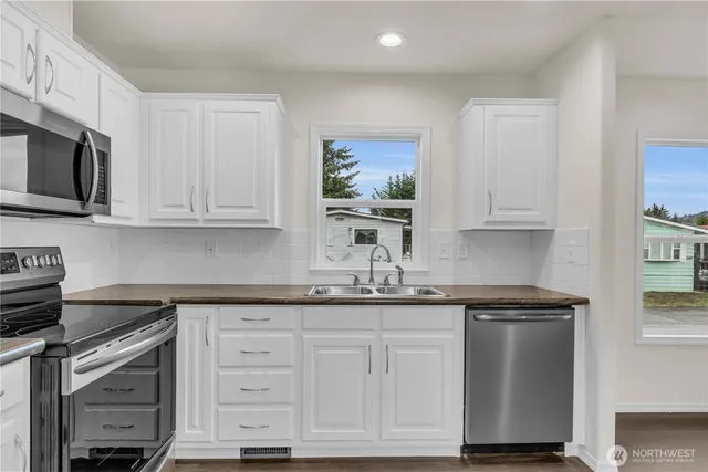 a kitchen with white cabinets and stainless steel appliances