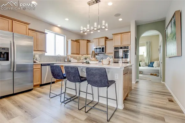 a kitchen with stainless steel appliances a dining table chairs refrigerator and cabinets