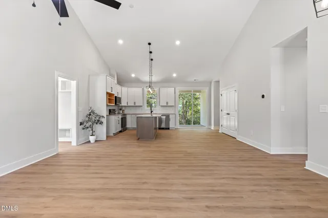a view of kitchen and empty room with wooden floor